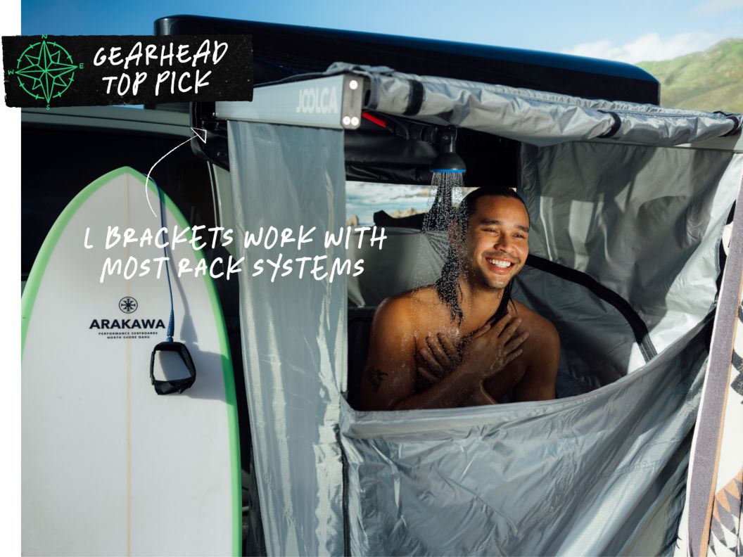 A man happily showers after surfing all day. Text overlay reads: Gearhead Top Pick, L brackets work with most rack systems.